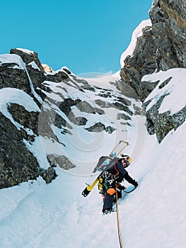 Ice climbing: mountaineer on a mixed route of snow and rock during the winter