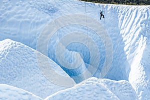 Ice climbing ropes on the Matanuska Glacier. A female guide climbs out of a deep canyon on one of the ropes