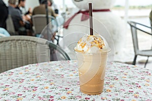 Ice coffee with cream on table. Caramel frappe coffee in the coffee shop.