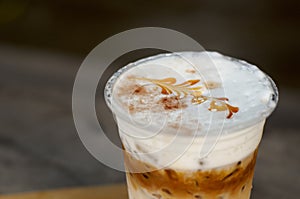 Ice coffee with creamy milk in a plastic glass is on a table, selective focus, latte art