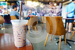 Ice coffee cup on wooden table in modern cafe