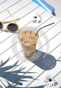 Ice coffee Cyprus Frappe Fredo top view on white table, with sunglasses. Summer minimalistic background, holiday or photo