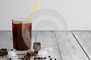 Ice coffee in a glass on gray wooden background