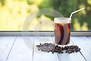 Ice coffee in a glass on gray wooden background