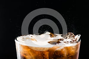 Ice cola with splashing CO bubbles in a glass