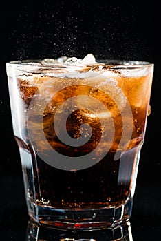 Ice cola with splashing CO bubbles in a glass