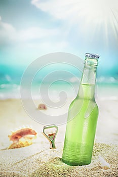 Ice cold bottle of lager or soda on a beach