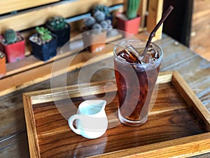 Ice cold brew coffee glass and milk jar on wooden tray