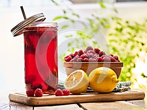 Ice cold drink glass with raspberry and lemon cocktail .