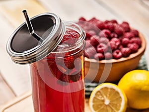 Ice cold drink glass with raspberry and lemon cocktail .