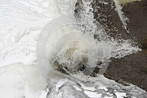 Ice cold water splashes from flowing river