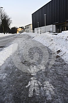 Ice covered sidewalk with a pedestrian path sign