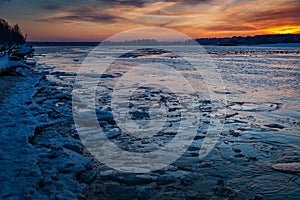 Ice covered with snow on frozen river water a sunset.