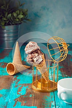 Ice cream with chocolate and caramel in waffle cone over wooden backgroundl