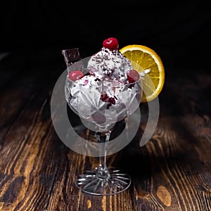 Ice cream with chocolate, cherry and orange in a crystal glass