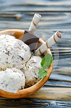 Ice cream with chocolate crumb in a wooden bowl.