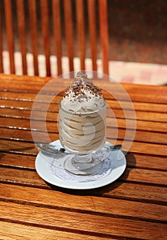 Ice cream with chocolate shavings on white saucer with spoon
