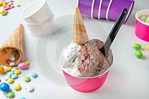 ice-cream with chocolate and stracciatella cream in tub with biscuits cones and sugared almonds