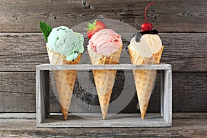 Ice cream cone assortment against a wood background, mint, strawberry and vanilla flavors