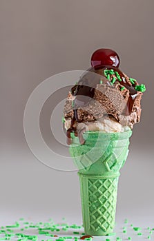 Ice cream cone with chocolate and vanilla sorbet with dripping chocolate syrup and cherry with text space