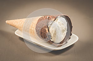 ice cream with cone in chocolate on a white plate/ice cream with cone in chocolate on a white plate on a dark background