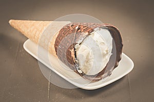 ice cream with cone in chocolate on a white plate/ice cream with cone in chocolate on a white plate, selective focus