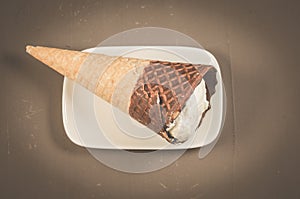 ice cream with cone in chocolate on a white plate/ice cream with cone in chocolate on a white plate, top view