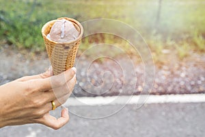 Ice cream cone filled with twirled softserve in hand / public park background photo