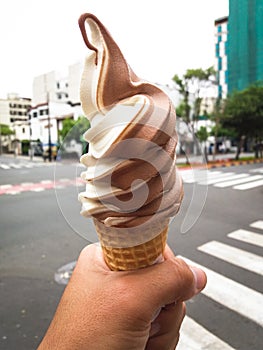 Ice cream cone held by a hand in the street