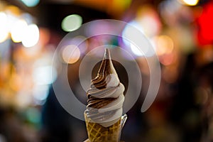 Ice cream cone held up on night bokeh