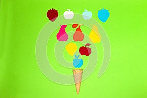 ice cream cone with various colorful paper fruits on a green background, creative art summer concept