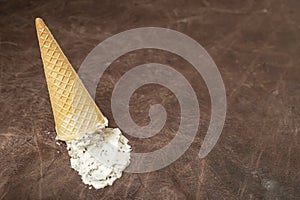 ice cream cone and white ice cream spilled on brown textured leather