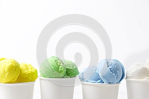 Ice cream with different flavours in paper cups against white wall.Concept of summer sweet menu