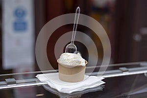 Ice cream in eco paper pot with transparent spoon on top, zero waste concept