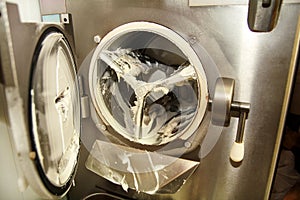 At ice cream factory is cleaning ice cream maker machine from the ice cream leavings.