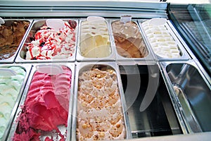 Ice cream fridge with creamy and fruit Italian ice cream steel serving counter with many of refreshing sweet scoopable flavors.