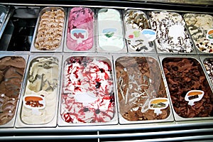 Ice cream fridge with creamy and fruit Italian ice cream steel serving counter with many of refreshing sweet scoopable flavors.