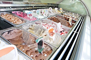 Ice cream fridge with creamy and fruit Italian ice cream steel serving counter with many of refreshing sweet scoopable flavors.