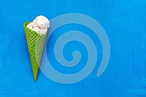 Ice cream in a green waffle cone on a blue background, flat lay. Top view, copy space. Summer refreshing dessert