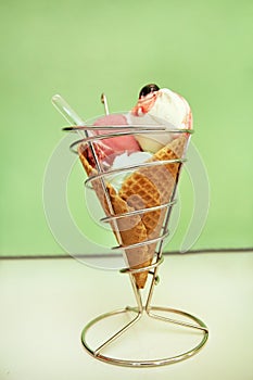 Ice Cream Holders. Strawberry, mint, vanilla with sour cherry ice cream in large waffle cone in holder, spoon.