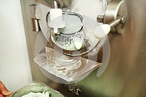 Ice cream making machine produces of mint ice cream flavors and it falls into steel container.