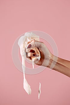 Ice cream is melting in hand, fist squeezes ice cream on a pink background