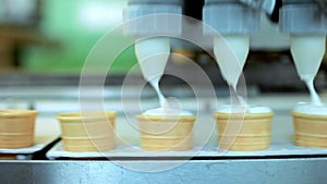 Ice cream pouring in waffle cones. Automated production line at food factory