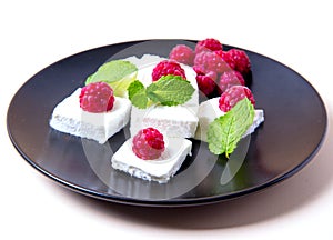 Ice cream with raspberries and mint on a black plate