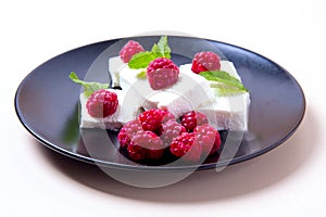 Ice cream with raspberries and mint on a black plate