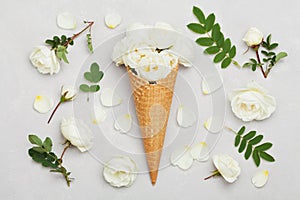 Ice cream of rose flowers in waffle cone on light gray background from above, beautiful floral decoration, vintage color, flat lay