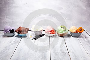 Ice cream scoops of different colors and flavours with berries, nuts and fruits decoration on white background