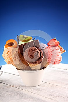 Ice cream scoops of different colors and flavours with berries, nuts and fruits decoration on white background