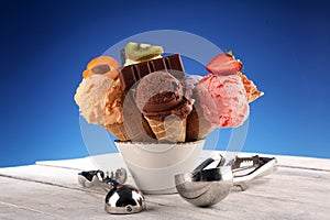 Ice cream scoops of different colors and flavours with berries, nuts and fruits decoration on white background