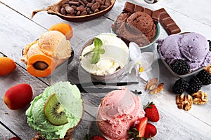 Ice cream scoops of different colors and flavours with berries, nuts and fruits decoration on white background